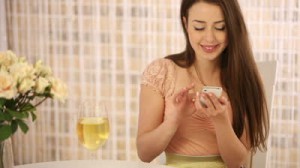rsz_stock-footage-beautiful-young-woman-sitting-at-cafe-with-glass-of-wine-using-cellphone-looking-at-camera-and